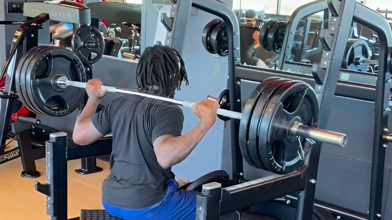 Client back squatting a heavy barbell inside a power rack